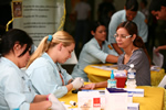 Estudiantes de enfermería realizando unas pruebas de sangre a una profesora en una feria de salud