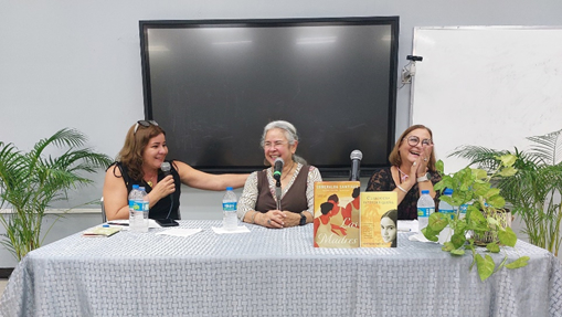 Las profesoras Emma Domenech Flores y Evelyn Jiménez Rivera junto a la escritora Esmeralda Santiago sentadas en una mesa