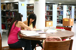 Estudiantes haciendo tarea sentadas en una mesa de la Biblioteca